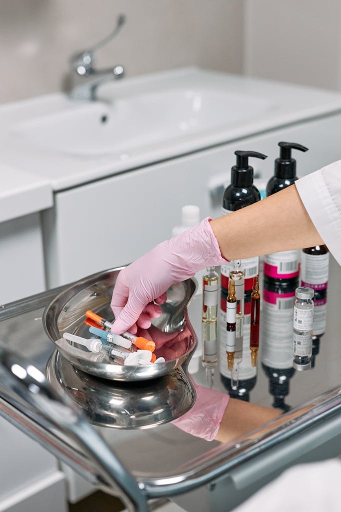A cosmetologist arranges skincare products and syringes in a clinical setting.