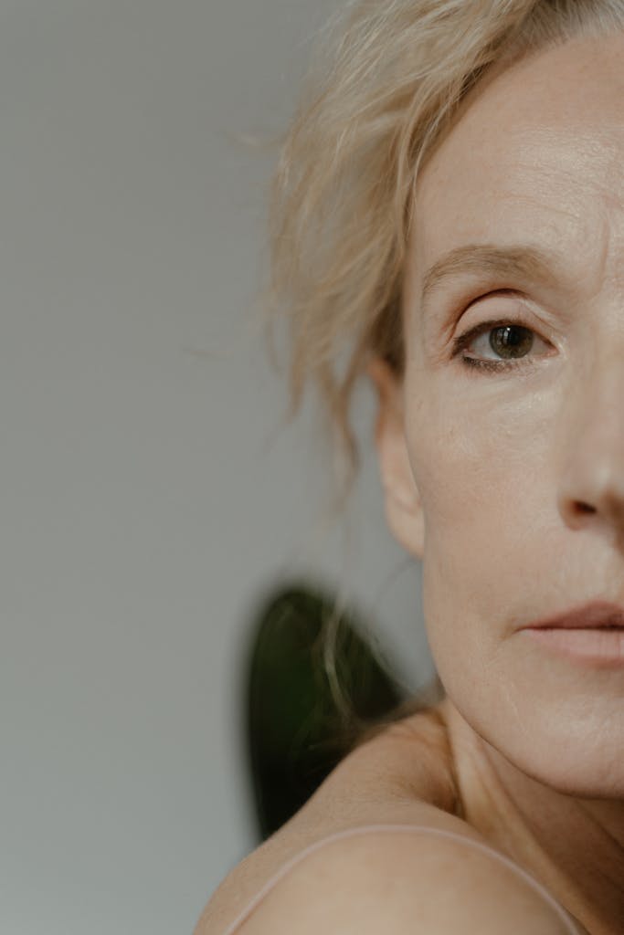 Artistic close-up portrait of a senior woman with a minimalist background conveying elegance and introspection.