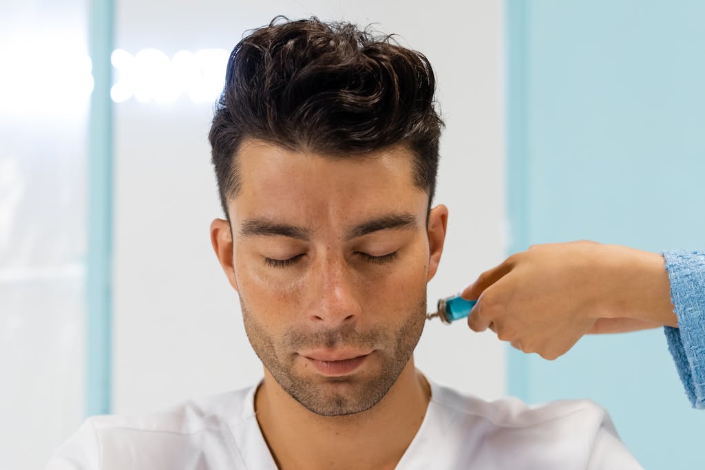 Close-up of a man receiving a facial skincare treatment in a spa room.