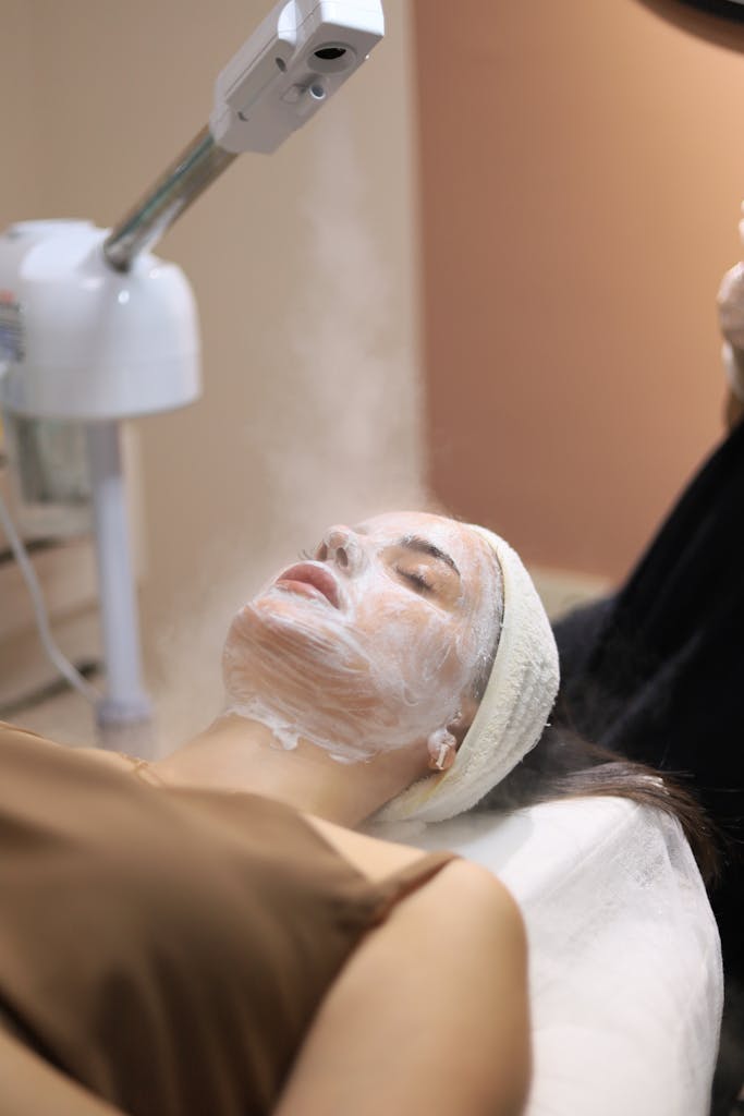 Woman enjoying a facial steam treatment in a serene spa setting.