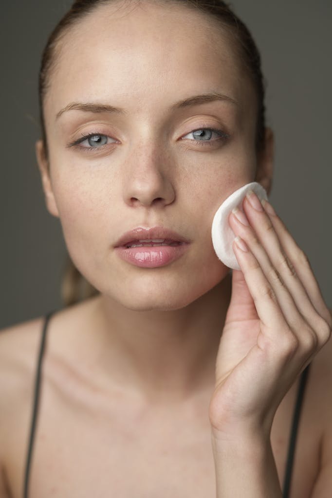 Young woman using a cotton pad for skincare, highlighting beauty routine.