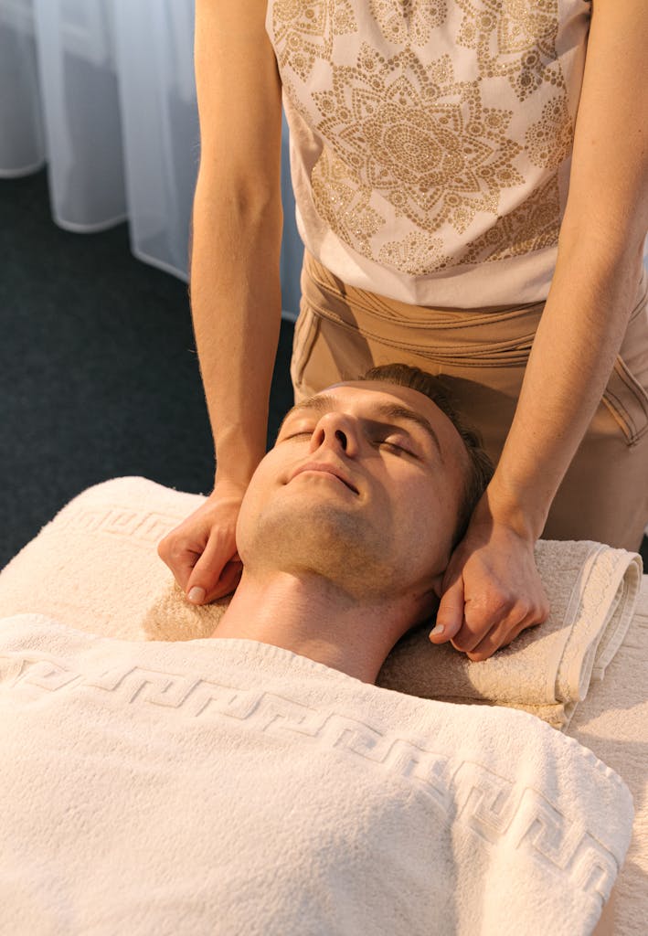 A man receiving a relaxing massage therapy session in a serene spa setting, promoting wellness.