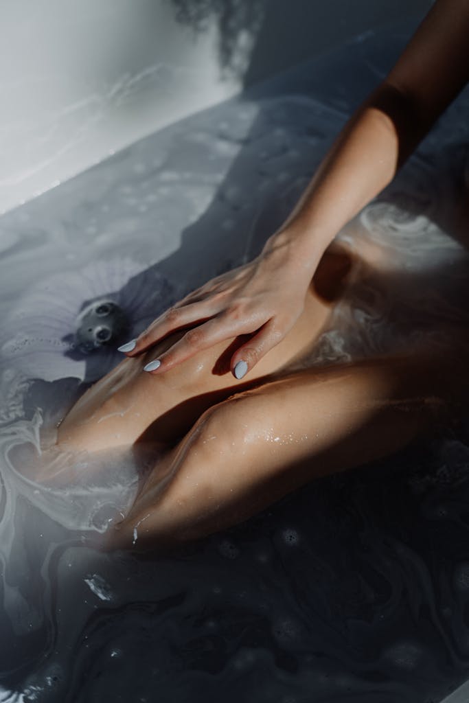 A serene and calming bath scene featuring bubbles and a gentle hand resting on a submerged body in warm water.